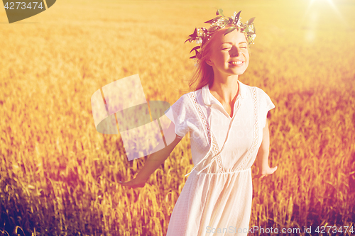 Image of happy young woman in flower wreath on cereal field