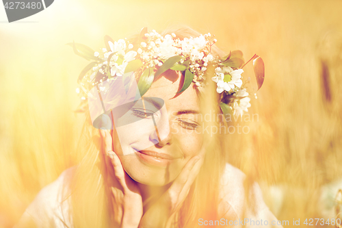 Image of happy woman in wreath of flowers on cereal field