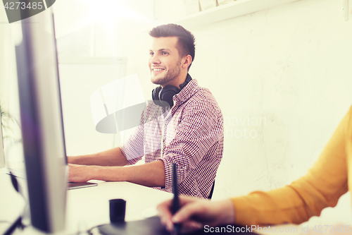 Image of happy creative team with computer and pen tablet