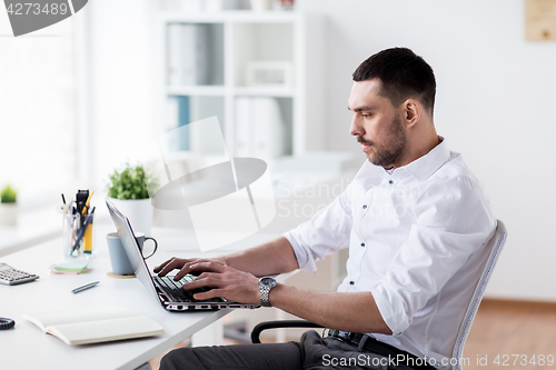 Image of businessman typing on laptop at office