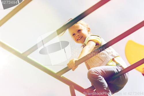 Image of happy little girl climbing on children playground