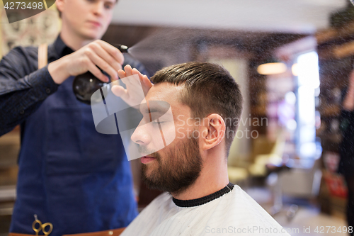 Image of barber applying styling spray to male hair