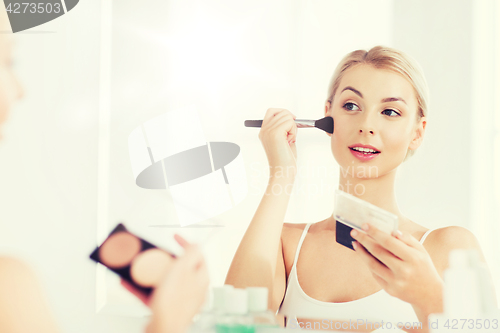 Image of woman with makeup brush and foundation at bathroom