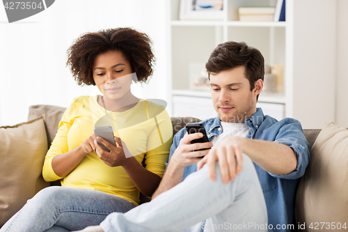 Image of happy couple with smartphones at home