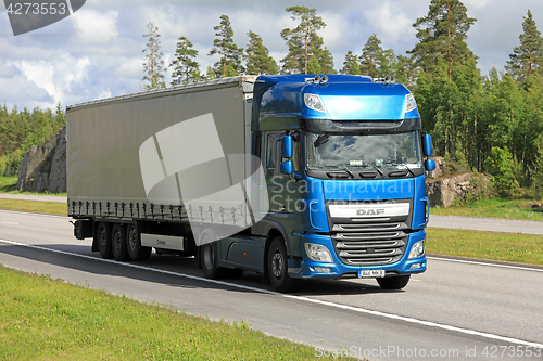 Image of Blue DAF XF semi trailer road transport at summer