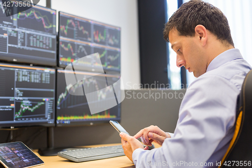 Image of Stock broker trading online with mobile phone application.