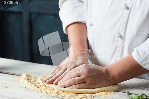 Image of Closeup hand of chef baker in white uniform making pizza at kitchen