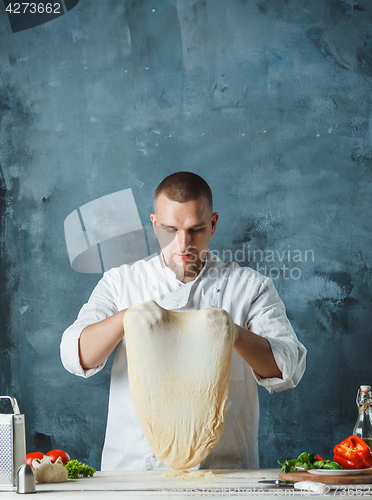 Image of Closeup hand of chef baker in white uniform making pizza at kitchen