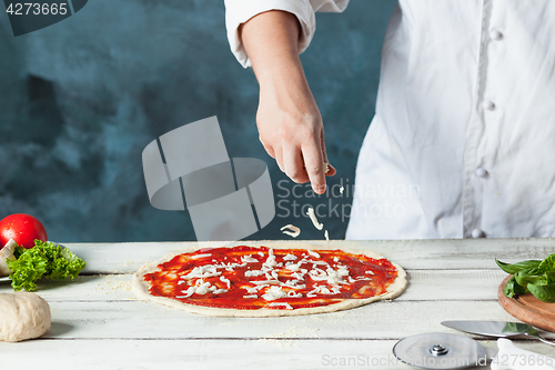 Image of Closeup hand of chef baker in white uniform making pizza at kitchen