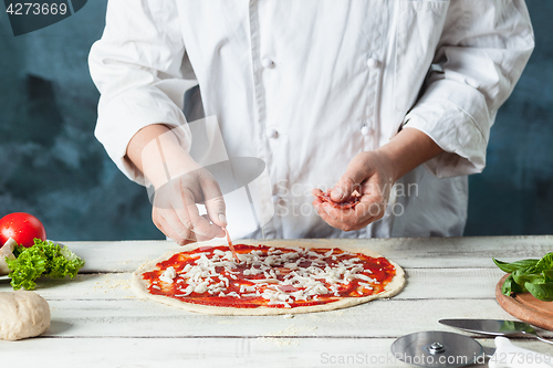 Image of Closeup hand of chef baker in white uniform making pizza at kitchen