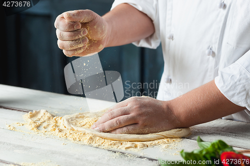 Image of Closeup hand of chef baker in white uniform making pizza at kitchen