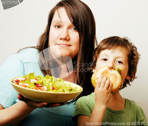 Image of mature woman holding salad and little cute boy with hamburger te