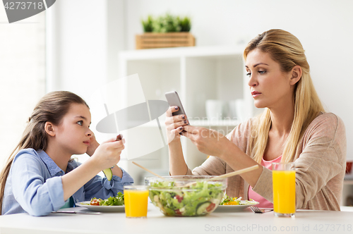 Image of sad girl looking at her mother with smartphone