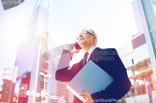 Image of senior businessman calling on smartphone in city