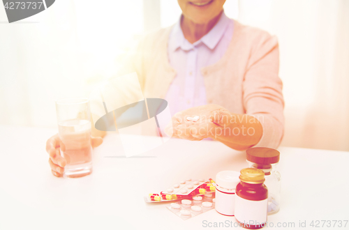 Image of happy senior woman with water and pills at home