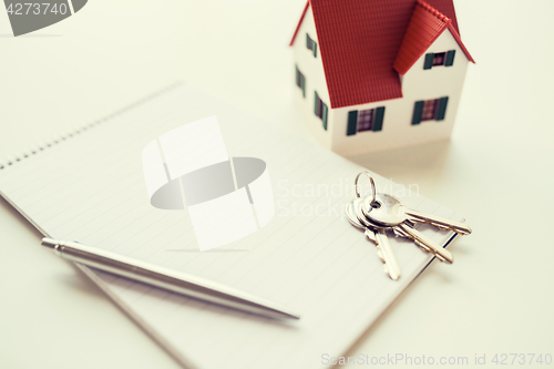 Image of close up of home model, house keys and notebook