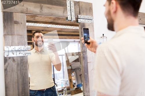 Image of man taking selfie by smartphone at barbershop