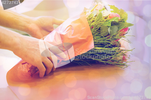 Image of florist wrapping flowers in paper at flower shop