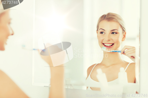 Image of woman with toothbrush cleaning teeth at bathroom