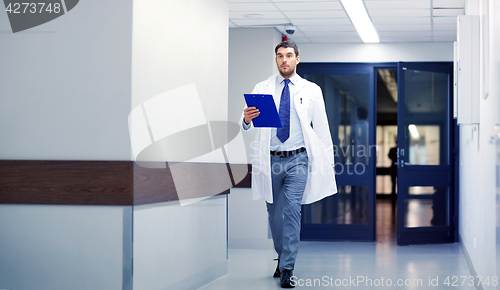 Image of doctor with clipboard walking along hospital