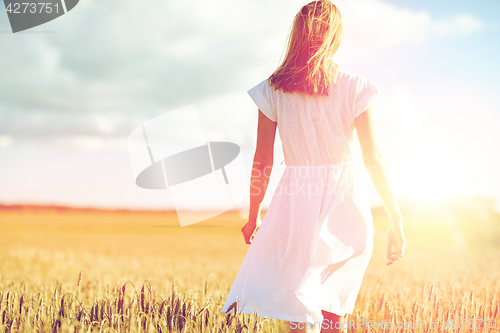 Image of young woman in white dress walking along on field