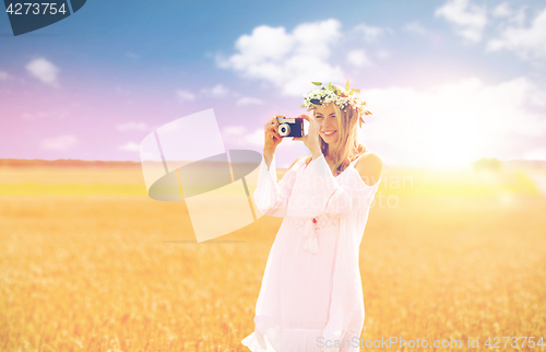 Image of happy woman with film camera in wreath of flowers