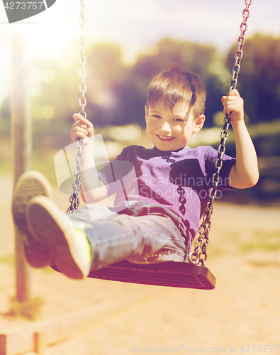 Image of happy little boy swinging on swing at playground