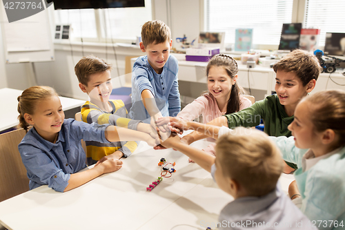 Image of happy children holding hands at robotics school