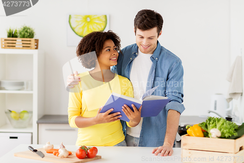 Image of happy couple with cooking book at home kitchen