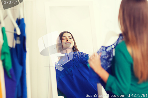 Image of happy woman choosing clothes at home wardrobe