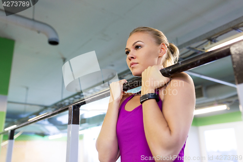 Image of woman exercising and doing pull-ups in gym