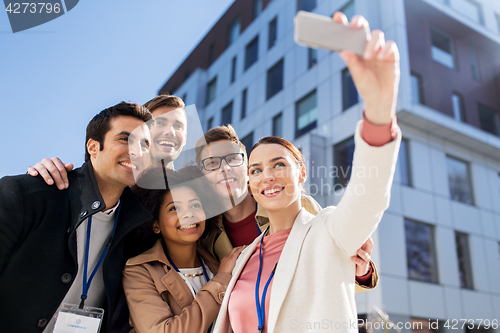 Image of happy people with conference badges taking selfie