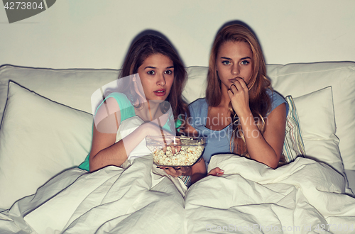 Image of friends with popcorn and watching tv at home