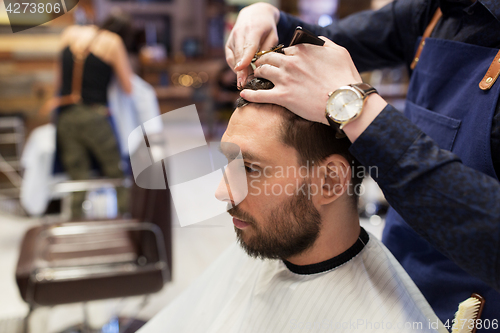 Image of man and barber cutting hair at barbershop