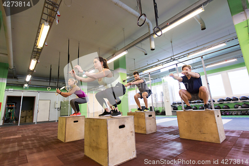 Image of group of people doing box jumps exercise in gym