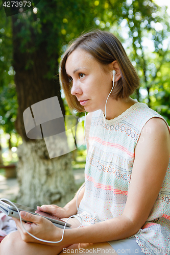 Image of Charming girl with gadget in park