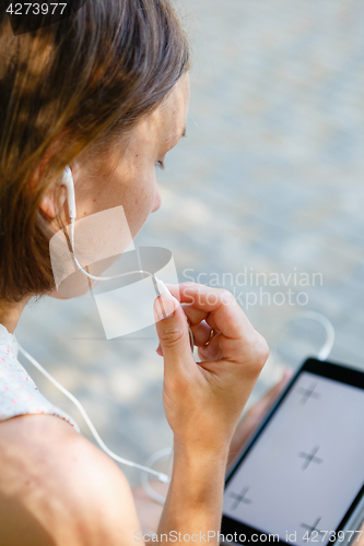 Image of Woman using headphones with tablet