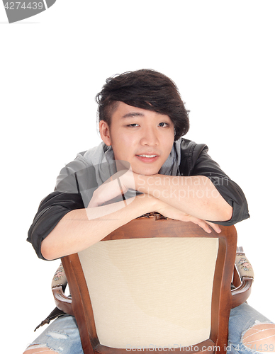 Image of Asian man sitting backwards on chair.