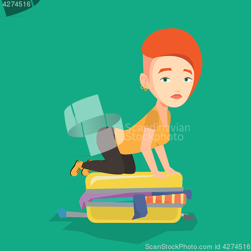 Image of Young woman trying to close suitcase.