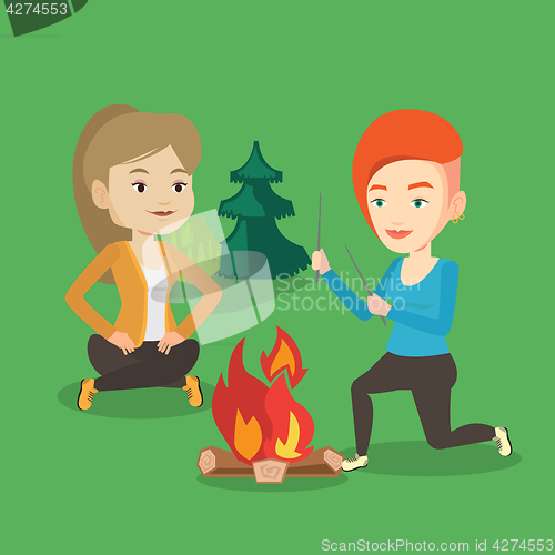 Image of Two friends sitting around bonfire in camping.