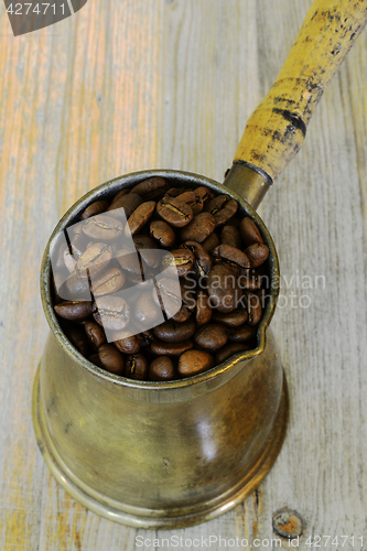 Image of arabic coffee pot on wooden background with beans