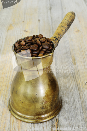 Image of arabic coffee pot on wooden background with beans