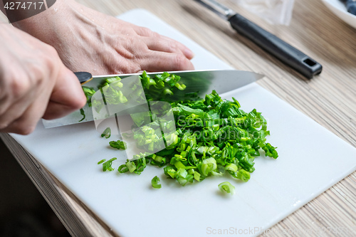 Image of Female hands chopping green onions 