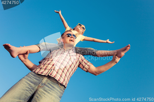 Image of Dad and daughter in sunglasses playing near a house at the day t