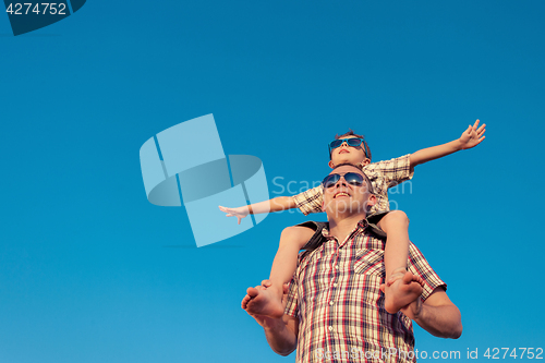 Image of Dad and son in sunglasses playing near a house at the day time.