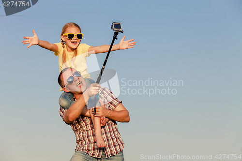 Image of Dad and daughter in sunglasses playing near a house at the day t