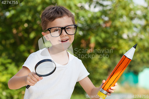 Image of Smiling young child in a uniform standing against a tree in the 