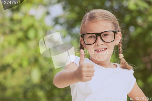 Image of Smiling young child in a uniform standing against a tree in the 