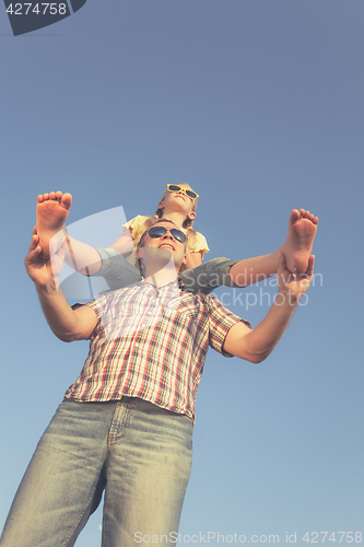 Image of Dad and daughter in sunglasses playing near a house at the day t