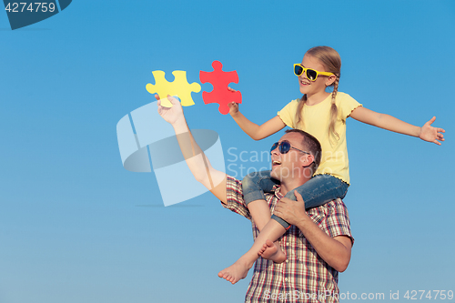 Image of Dad and daughter in sunglasses playing near a house at the day t